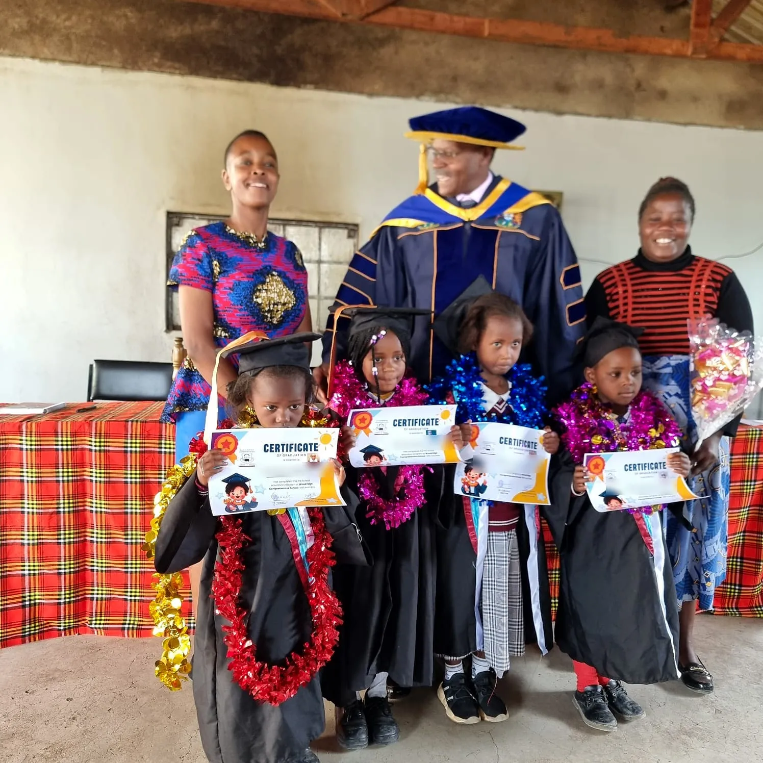 Teachers with pre-school graduates holding their certificates