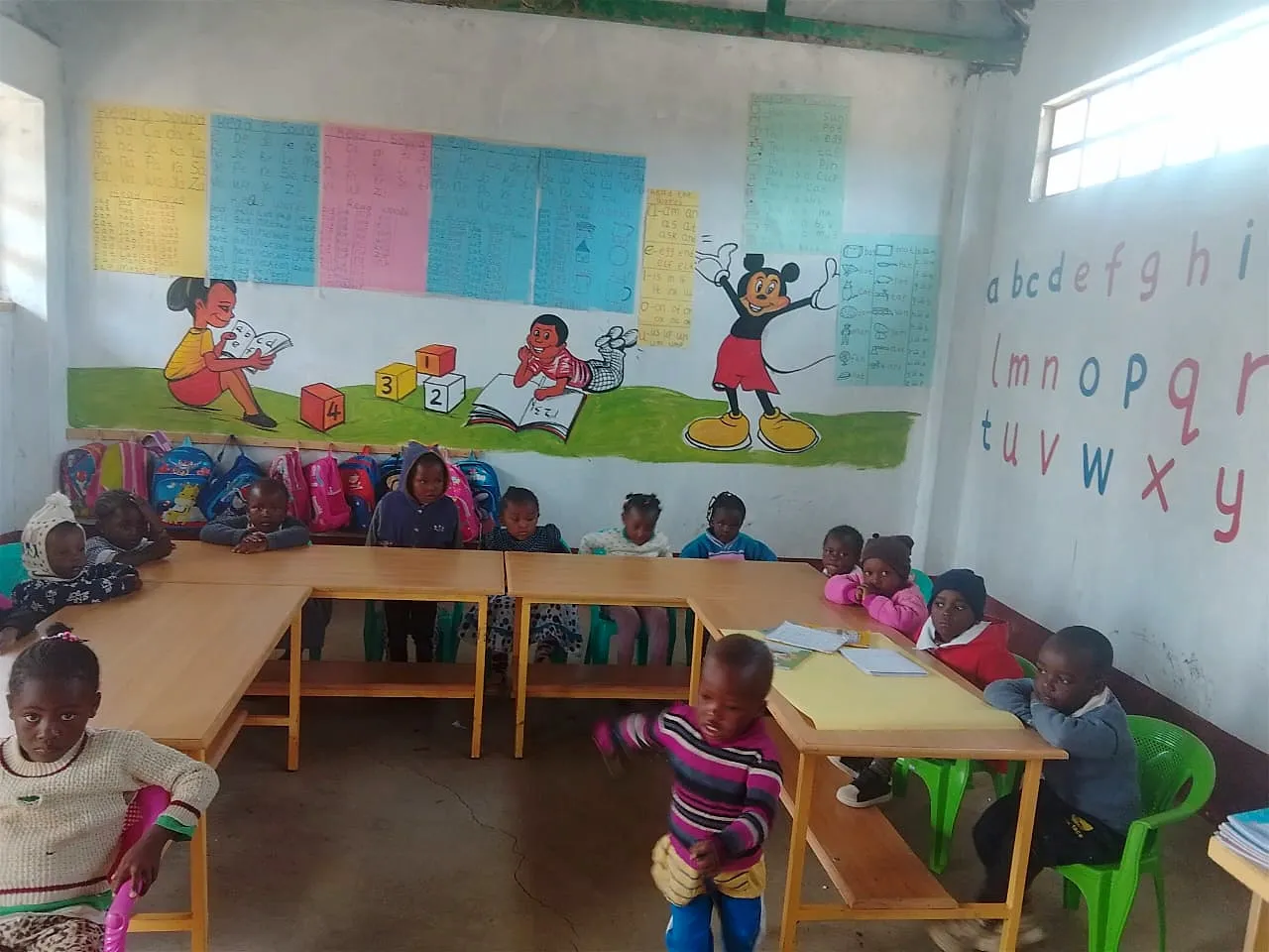 Pre-school learners at their tables in a brightly decorated classroom